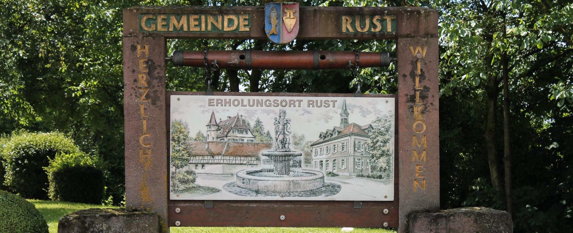 Willkommensschild Rust inmitten eines Blumenbeetes Willkommensschild Rusts mit Zeichnungen Ruster Sehenswürdigkeiten, inmitten eines Blumenbeetes