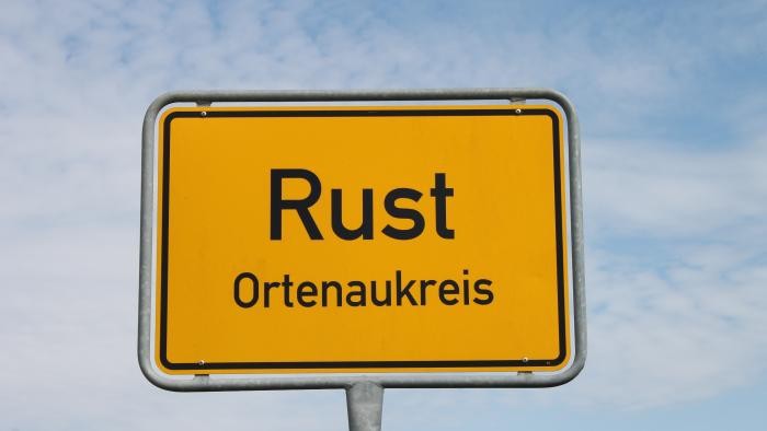 Ortsschild Rust gelbes Ortsschild von Rust mit blauem Himmel im Hintergrund